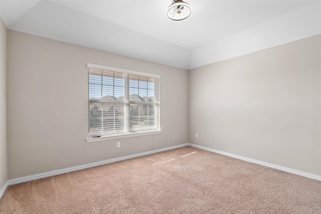 carpeted spare room featuring vaulted ceiling