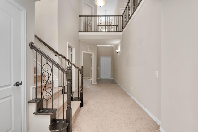 foyer entrance featuring a towering ceiling and carpet floors