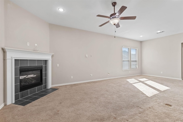 unfurnished living room with a tile fireplace, dark colored carpet, and ceiling fan