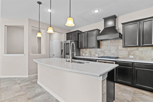 kitchen featuring sink, decorative light fixtures, an island with sink, and premium range hood