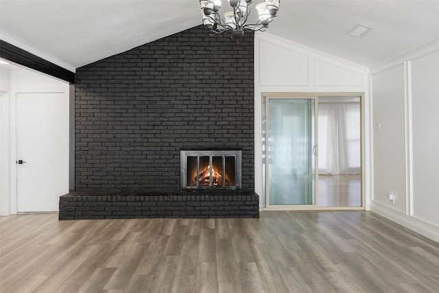 unfurnished living room with an inviting chandelier, light hardwood / wood-style flooring, brick wall, and vaulted ceiling