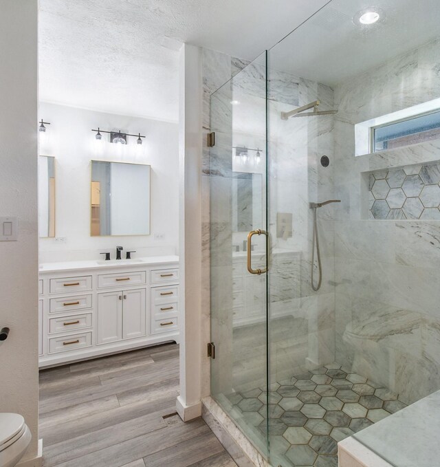 bathroom featuring toilet, hardwood / wood-style floors, vanity, and walk in shower