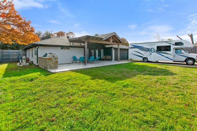 rear view of property featuring a pergola, a lawn, a patio area, and exterior kitchen