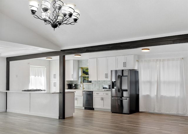 kitchen with tasteful backsplash, beamed ceiling, white cabinets, stainless steel fridge, and a healthy amount of sunlight