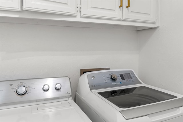 washroom with washer and clothes dryer and cabinets