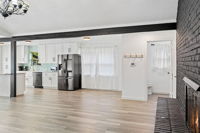 kitchen featuring white cabinetry, stainless steel appliances, and brick wall