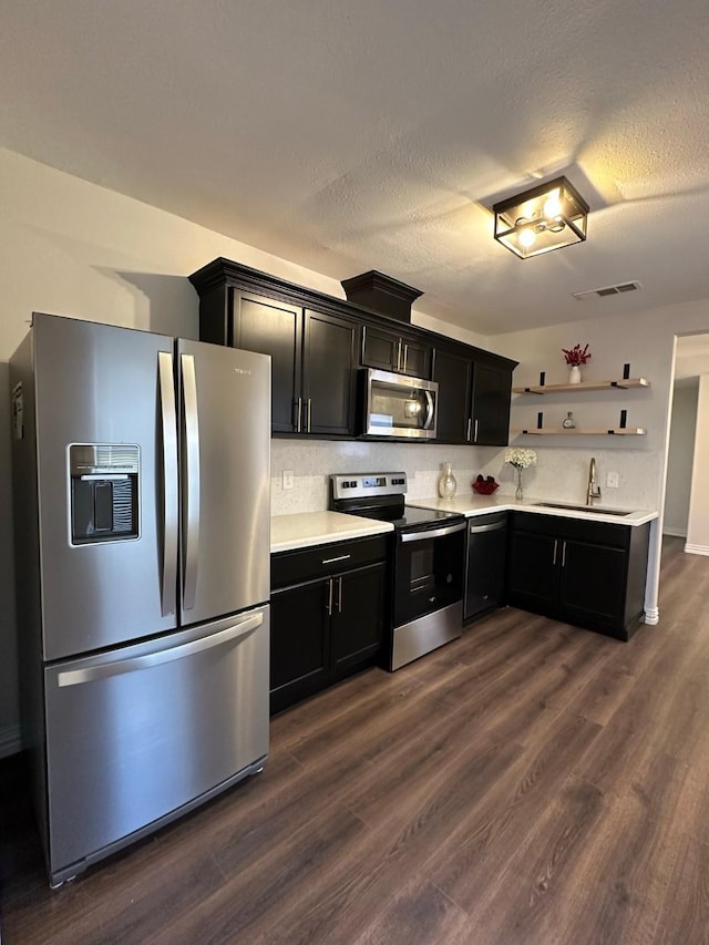 kitchen featuring sink, backsplash, dark wood-type flooring, and appliances with stainless steel finishes