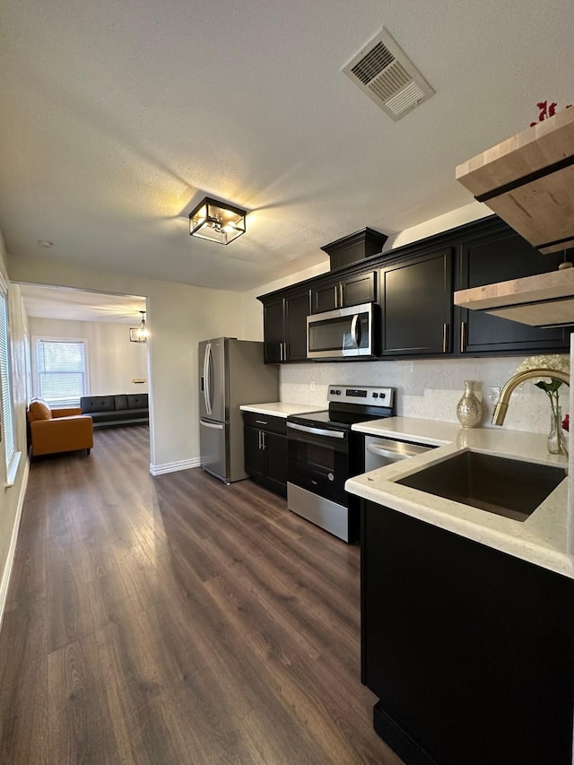 kitchen with a textured ceiling, sink, stainless steel appliances, and dark hardwood / wood-style floors