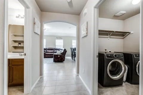 clothes washing area with washer and clothes dryer and light tile patterned floors