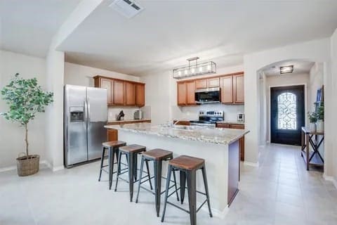 kitchen with pendant lighting, a breakfast bar area, light stone countertops, a kitchen island, and stainless steel appliances