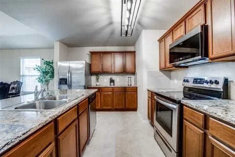 kitchen with light stone counters, sink, and stainless steel appliances