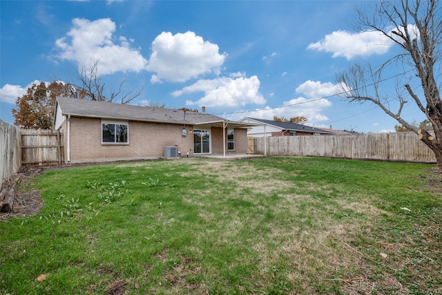 back of property with central AC unit, a patio area, and a lawn