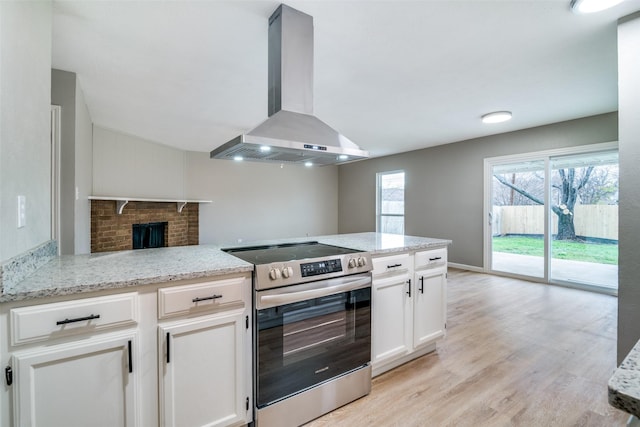 kitchen featuring electric stove, kitchen peninsula, white cabinets, and wall chimney range hood