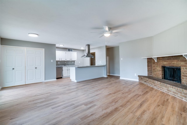 unfurnished living room with ceiling fan, light hardwood / wood-style floors, and a brick fireplace