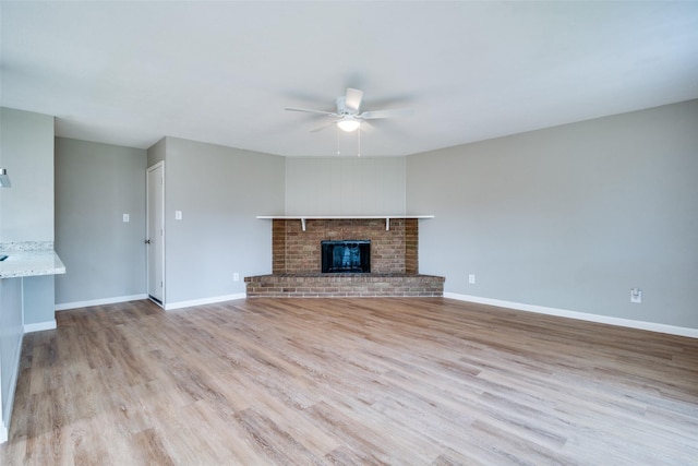 unfurnished living room featuring a fireplace, light wood-type flooring, and ceiling fan