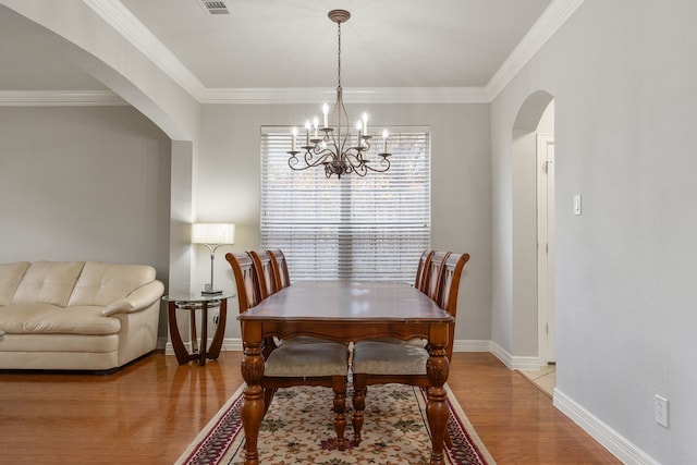 dining space with an inviting chandelier, hardwood / wood-style floors, and crown molding