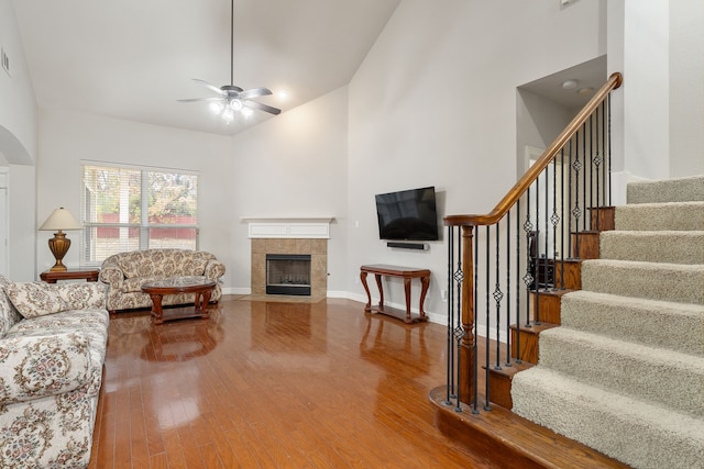 living room with a tile fireplace, hardwood / wood-style flooring, high vaulted ceiling, and ceiling fan