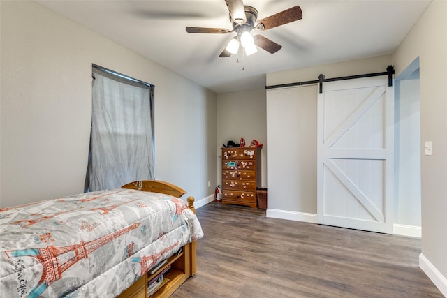 bedroom featuring hardwood / wood-style floors, a barn door, and ceiling fan