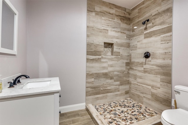 bathroom featuring vanity, toilet, and tiled shower