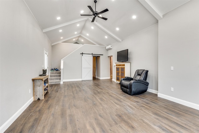 sitting room featuring ceiling fan, hardwood / wood-style floors, high vaulted ceiling, a wall mounted air conditioner, and a barn door