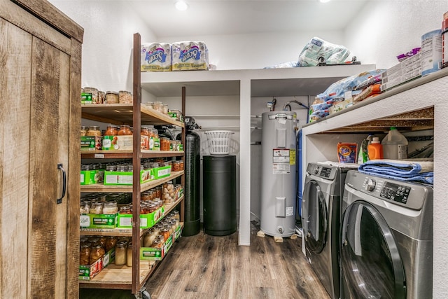 washroom with water heater, washer and dryer, and hardwood / wood-style flooring