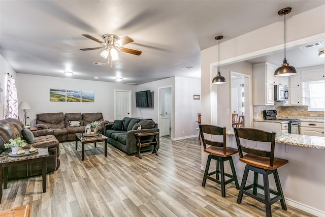 living room with light hardwood / wood-style flooring and ceiling fan