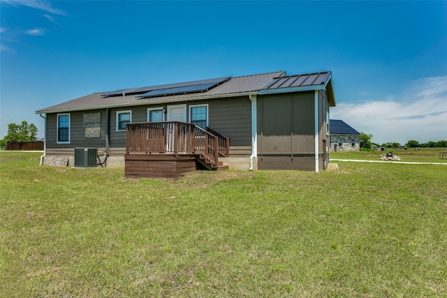 rear view of house with a lawn, solar panels, and central air condition unit