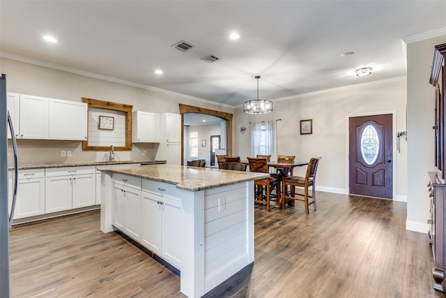 kitchen featuring sink, decorative light fixtures, white cabinets, and a kitchen island