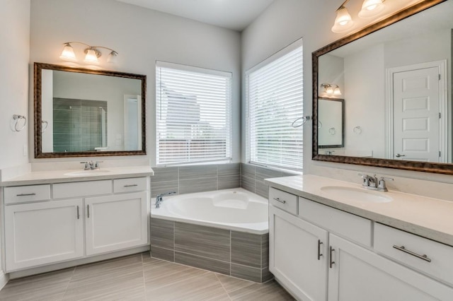 bathroom with tile patterned flooring, a relaxing tiled tub, and vanity