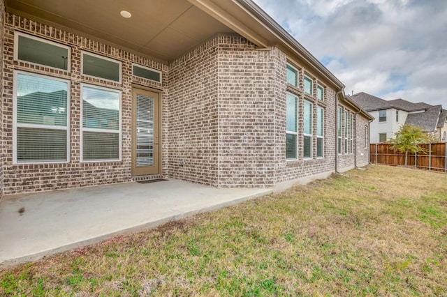 entrance to property with a lawn and a patio