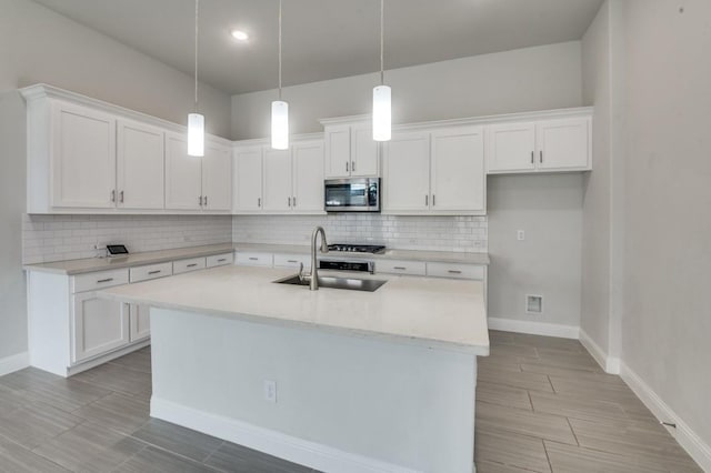 kitchen featuring white cabinets, pendant lighting, sink, and a kitchen island with sink