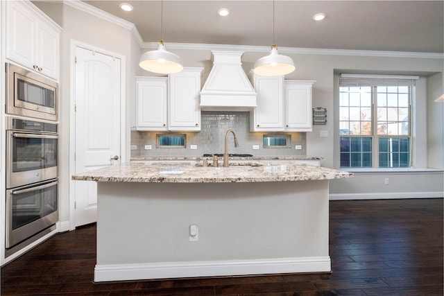 kitchen featuring light stone countertops, white cabinetry, stainless steel appliances, dark hardwood / wood-style floors, and an island with sink