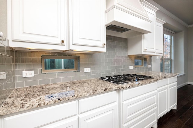 kitchen featuring stainless steel gas stovetop, custom exhaust hood, white cabinets, ornamental molding, and dark hardwood / wood-style flooring