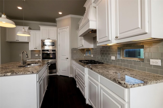 kitchen with premium range hood, stainless steel appliances, sink, white cabinets, and hanging light fixtures