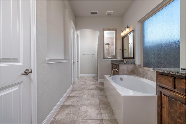 bathroom with tile patterned flooring, vanity, and a washtub