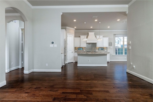 kitchen featuring light stone counters, a kitchen island with sink, and dark wood-type flooring