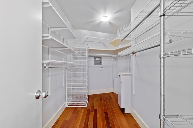 walk in closet with washer / clothes dryer, wood-type flooring, and electric panel