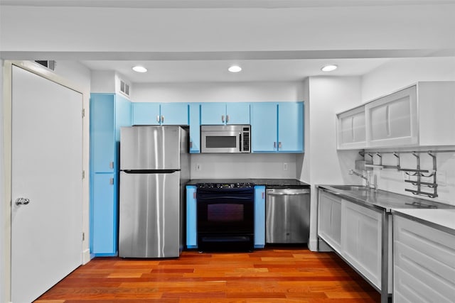 kitchen with sink, blue cabinets, stainless steel appliances, and light hardwood / wood-style flooring