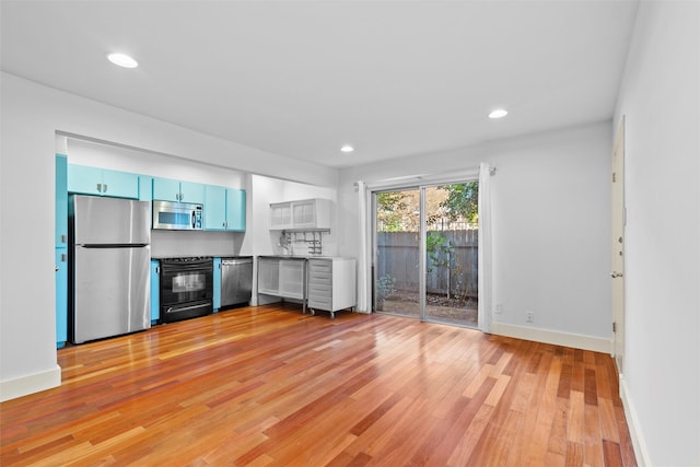 kitchen with blue cabinetry, appliances with stainless steel finishes, and light wood-type flooring