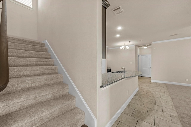 staircase with carpet flooring, ornamental molding, a notable chandelier, and sink