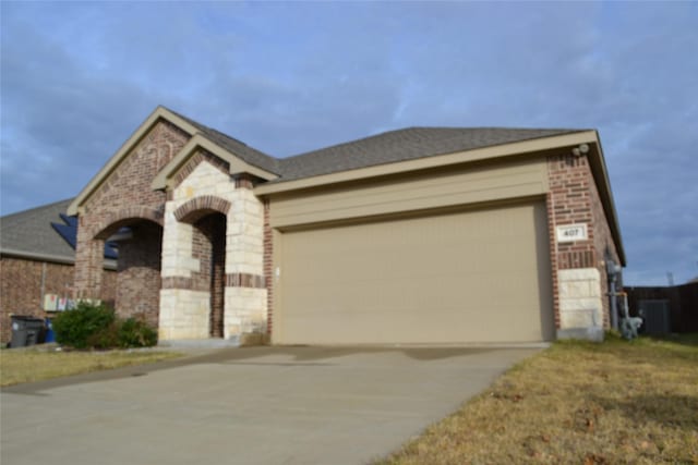 view of front facade featuring a garage, central AC, and a front yard