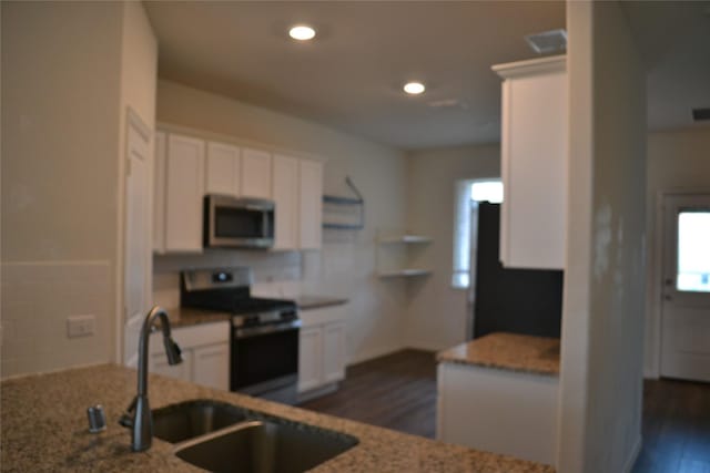 kitchen with sink, dark wood-type flooring, appliances with stainless steel finishes, white cabinetry, and stone countertops