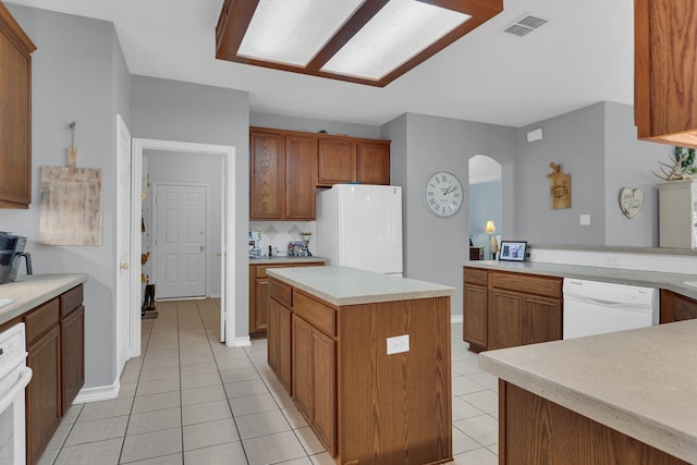 kitchen with decorative backsplash, a center island, white appliances, and light tile patterned floors