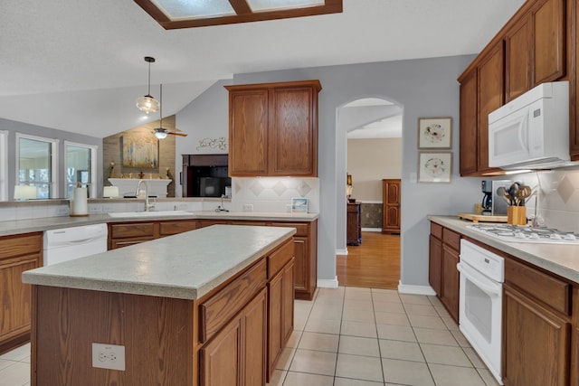 kitchen featuring a center island, lofted ceiling, white appliances, sink, and tasteful backsplash