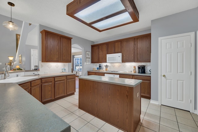 kitchen featuring backsplash, sink, light tile patterned floors, and pendant lighting