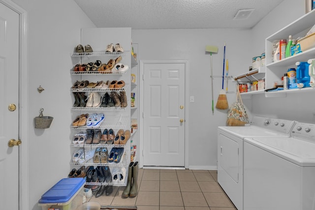 washroom featuring washer and dryer, a textured ceiling, and light tile patterned flooring