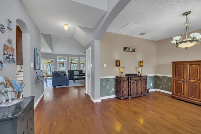 entryway featuring hardwood / wood-style floors, a textured ceiling, an inviting chandelier, and vaulted ceiling