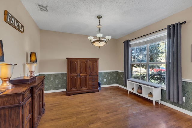 dining room with wood-type flooring, a textured ceiling, and a notable chandelier