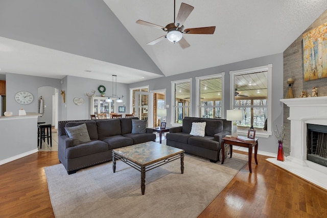 living room with hardwood / wood-style flooring, ceiling fan, and high vaulted ceiling