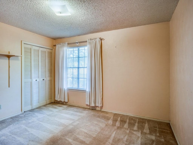 unfurnished bedroom with a closet, light colored carpet, and a textured ceiling